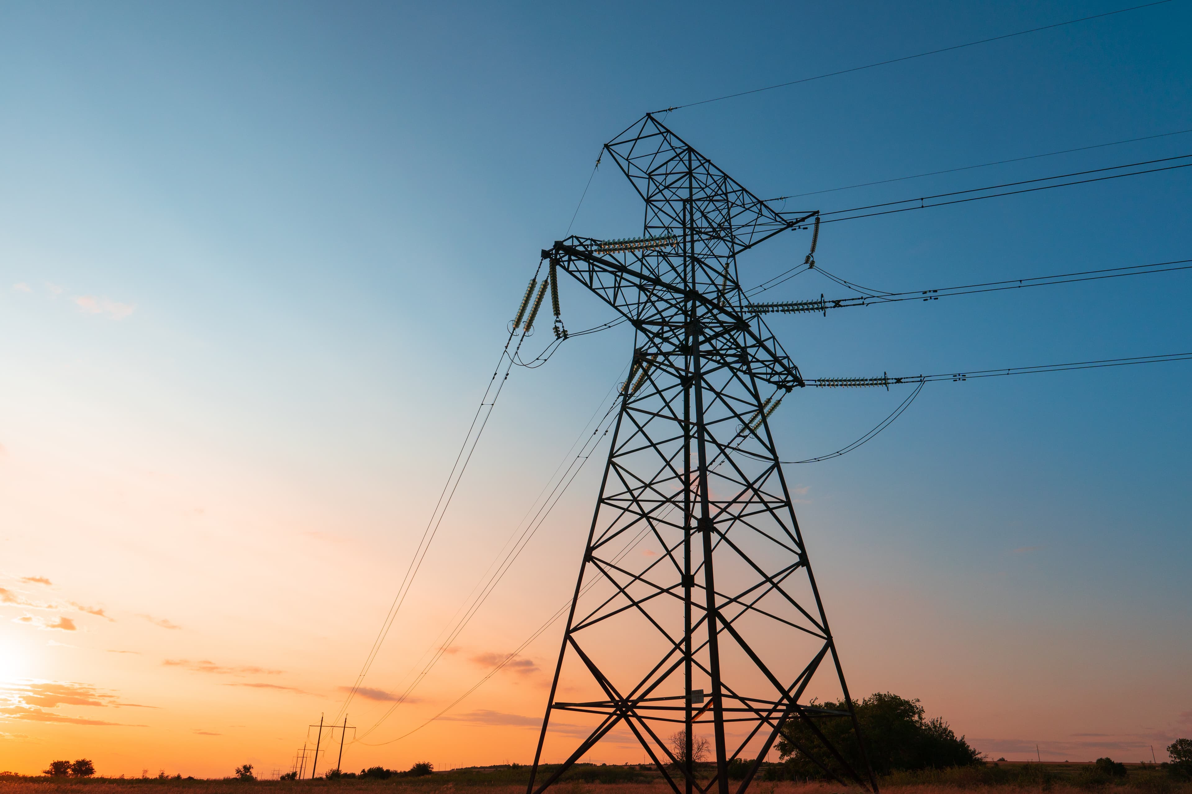 The silhouette of the evening electricity transmission pylon. Power transmission from a power plant to a city.