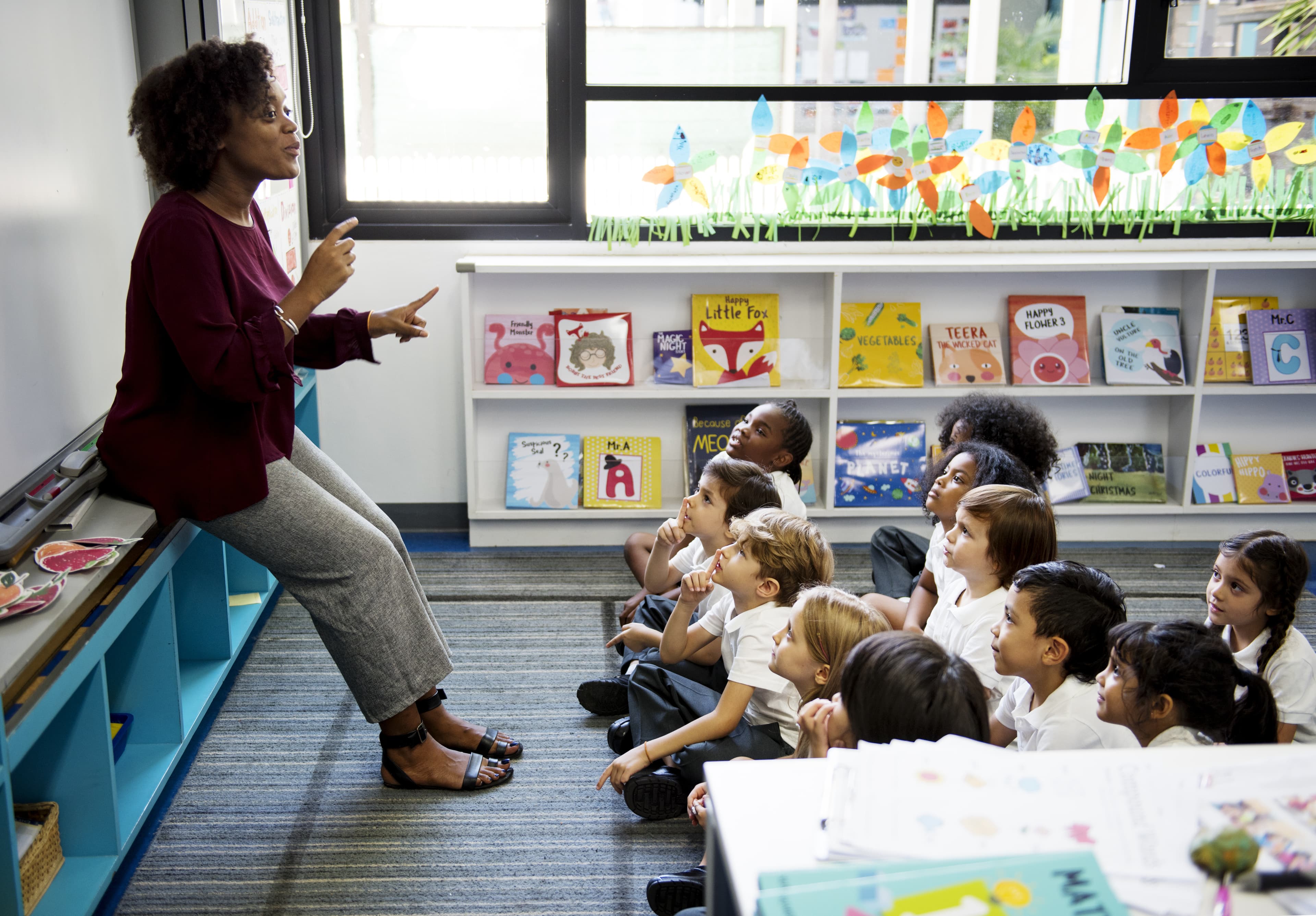 Kindergarten students sitting on the floor listening to teacher