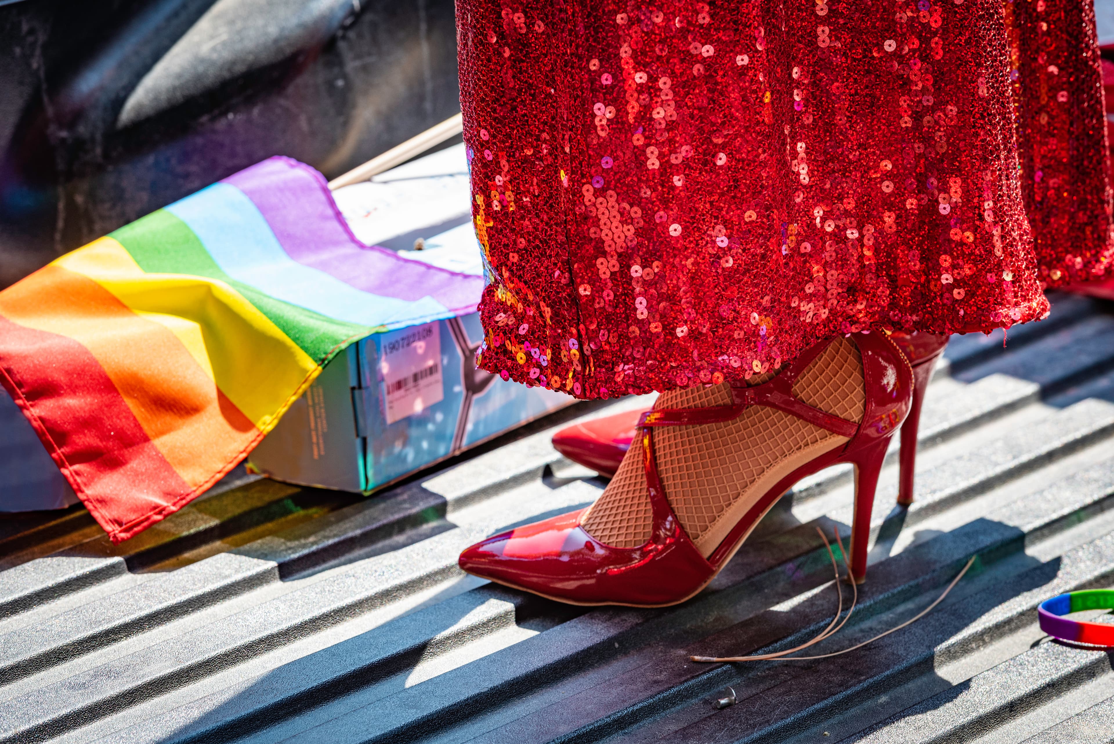 Close up of a drag queen's red stiletto heels, sparkly dress on