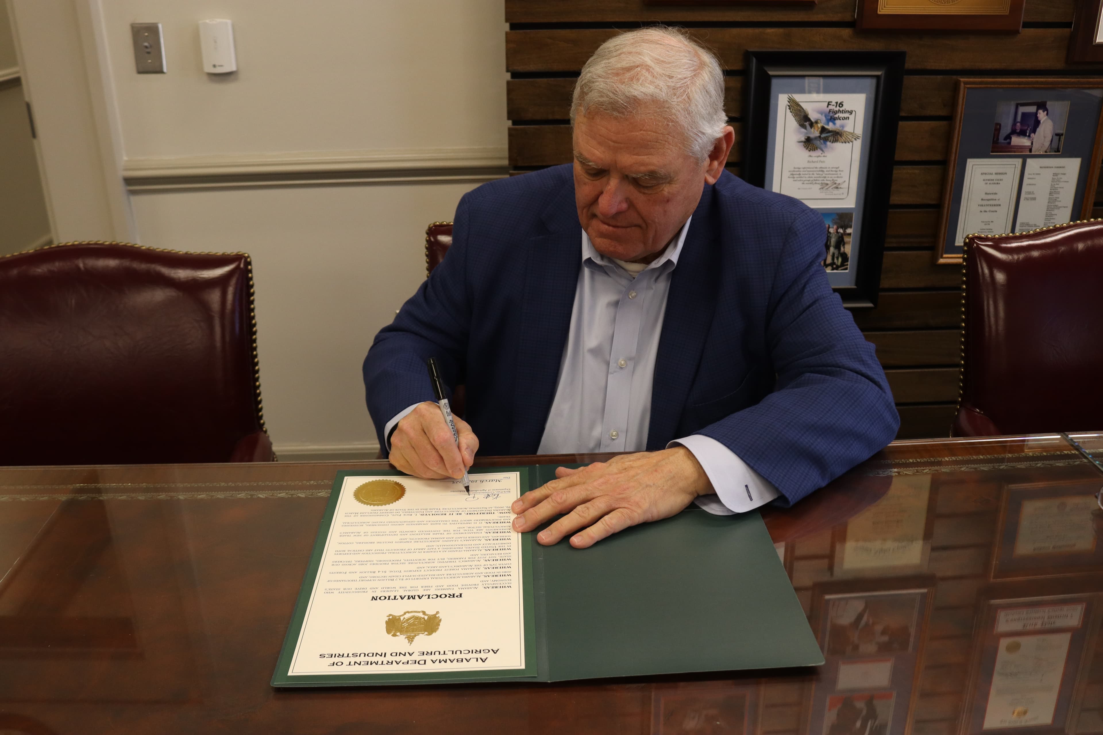 Commissioner Rick Pate signs a proclamation.