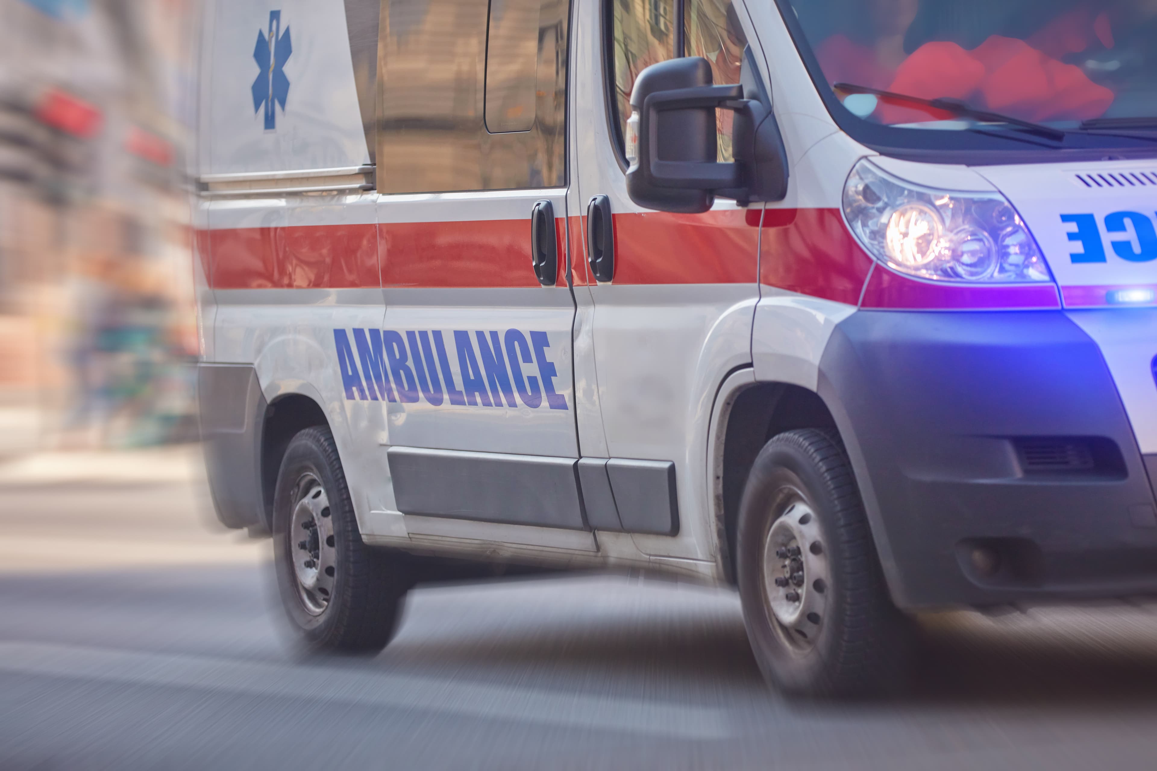 Paramedic 911 ambulance car running fast through the big city.