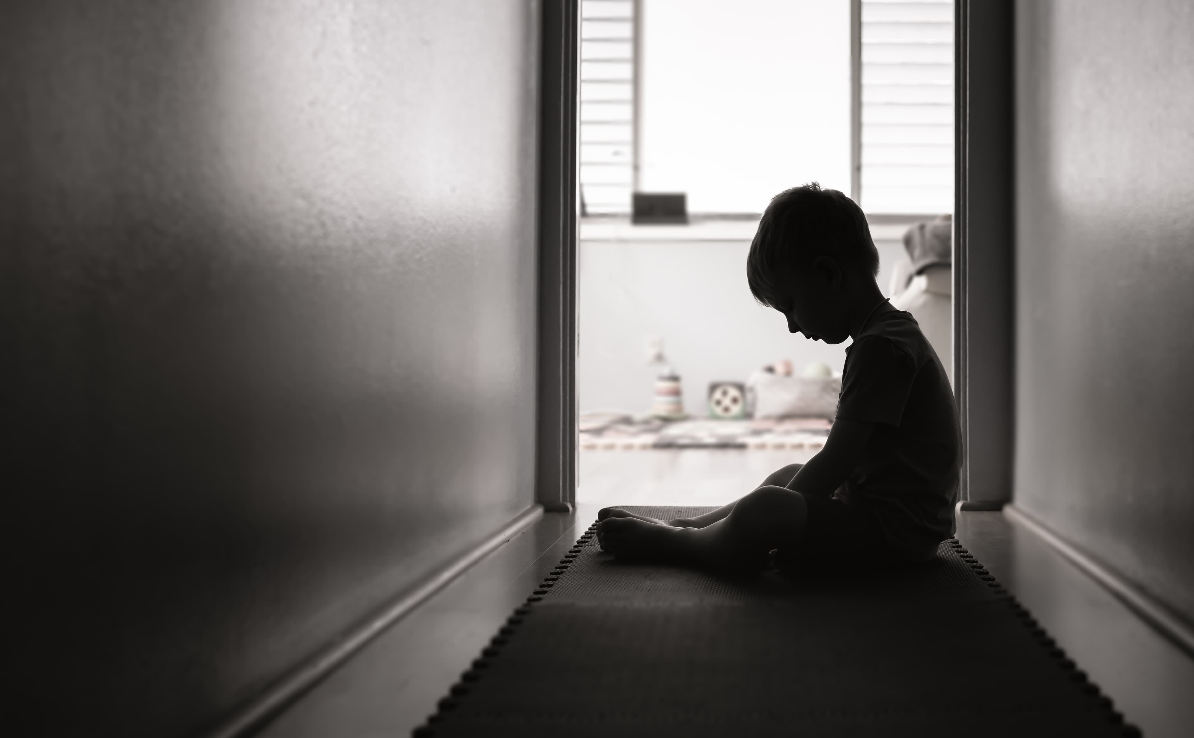 A boy looking down in a dark room.