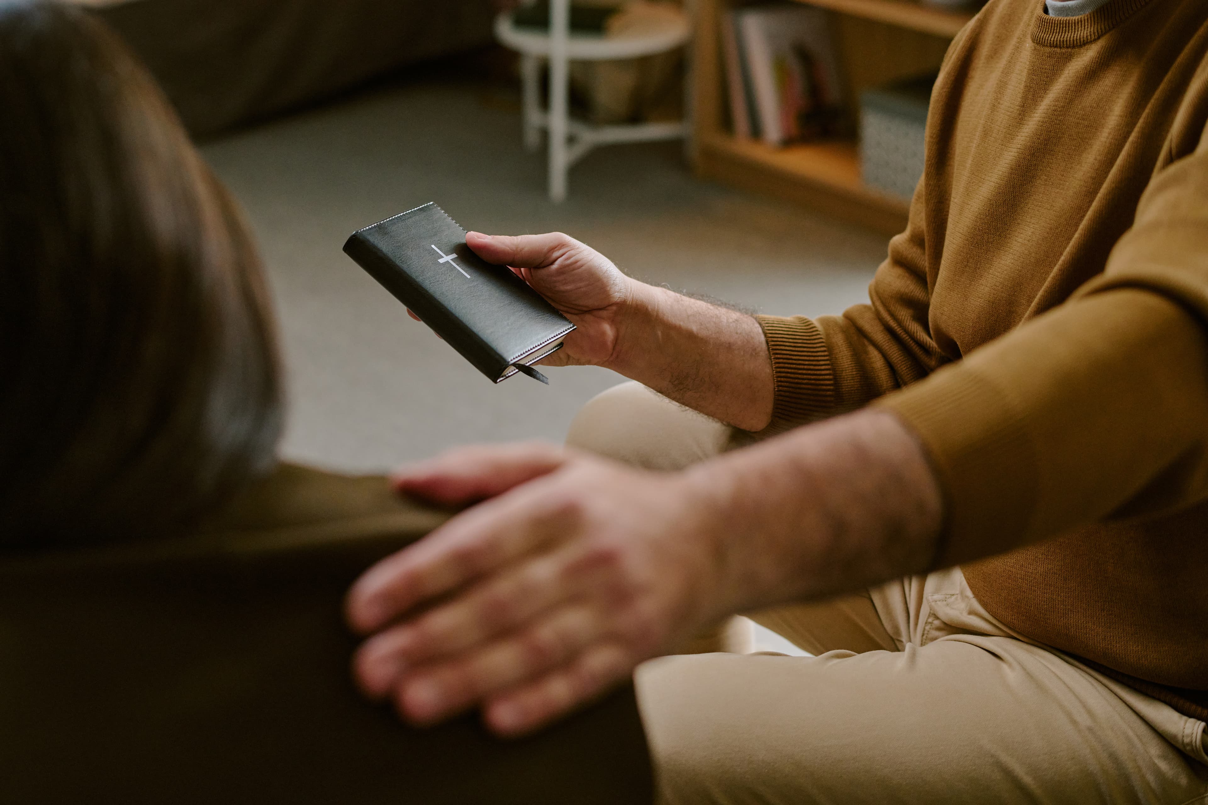 Middle Aged Man Comforting Woman While Holding Bible Indoors