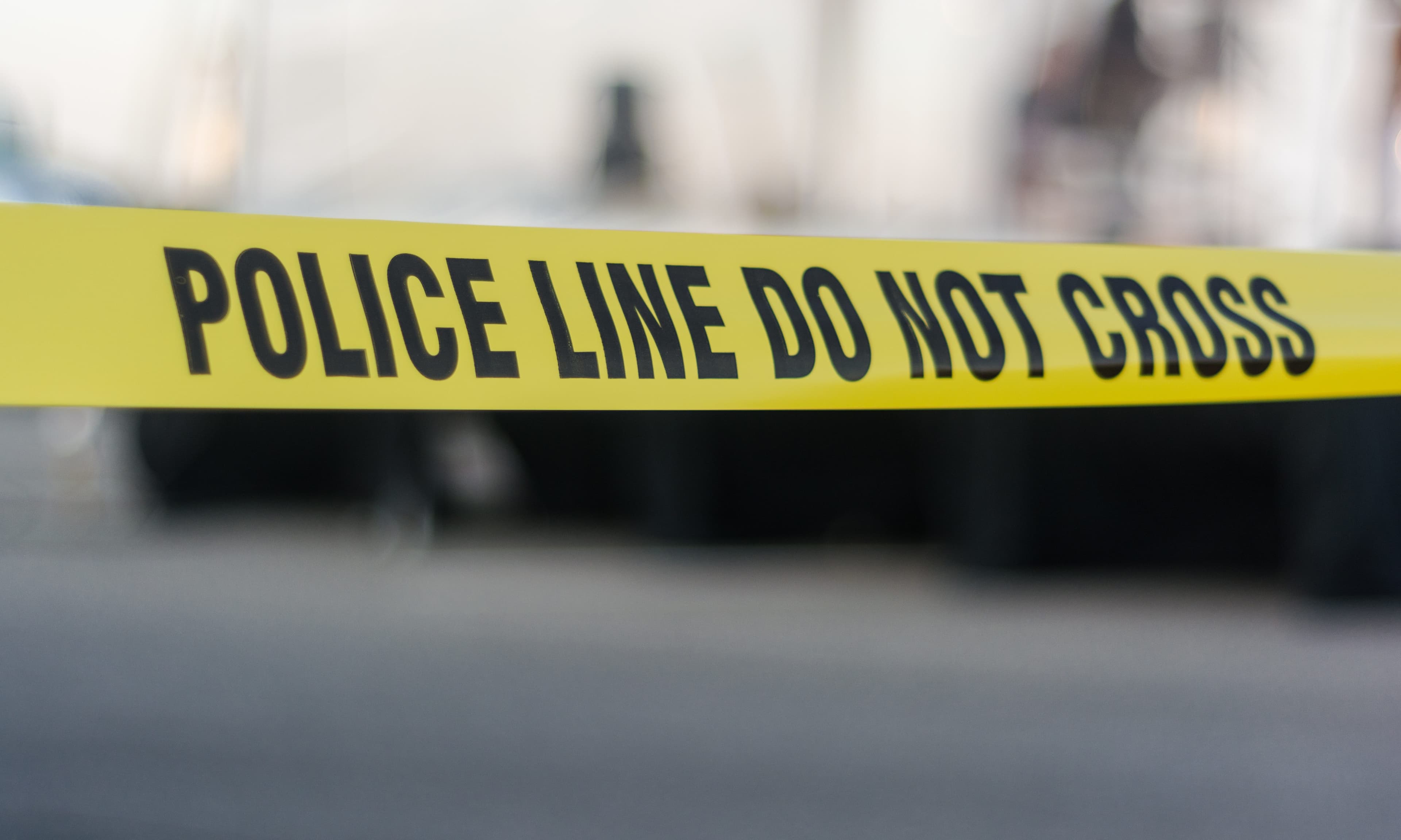 Yellow police tape with text: police line do not cross cornering off area from public access