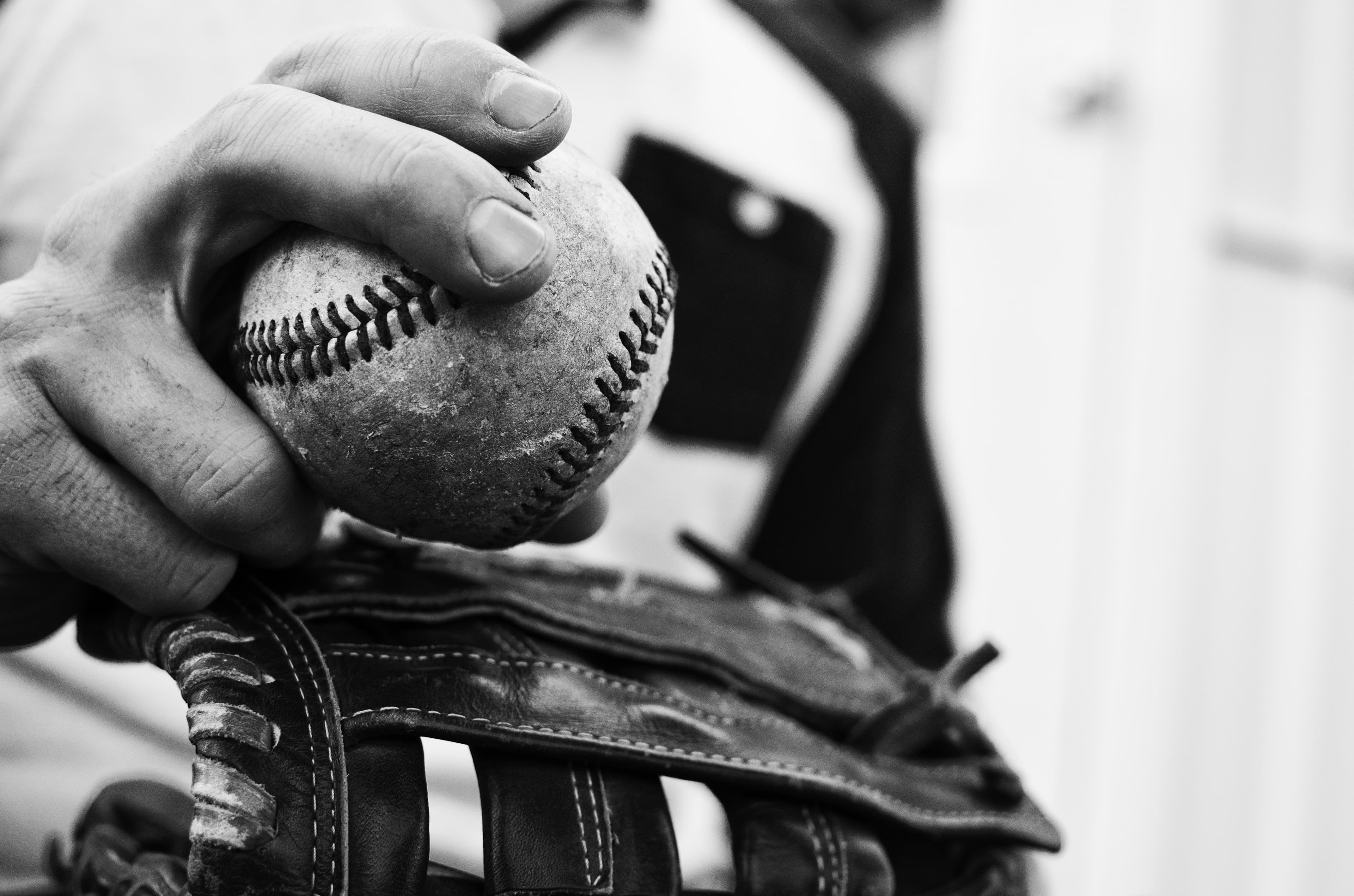 Old baseball in hand of a man who plays the sport. Great ball game or athletic background or print.