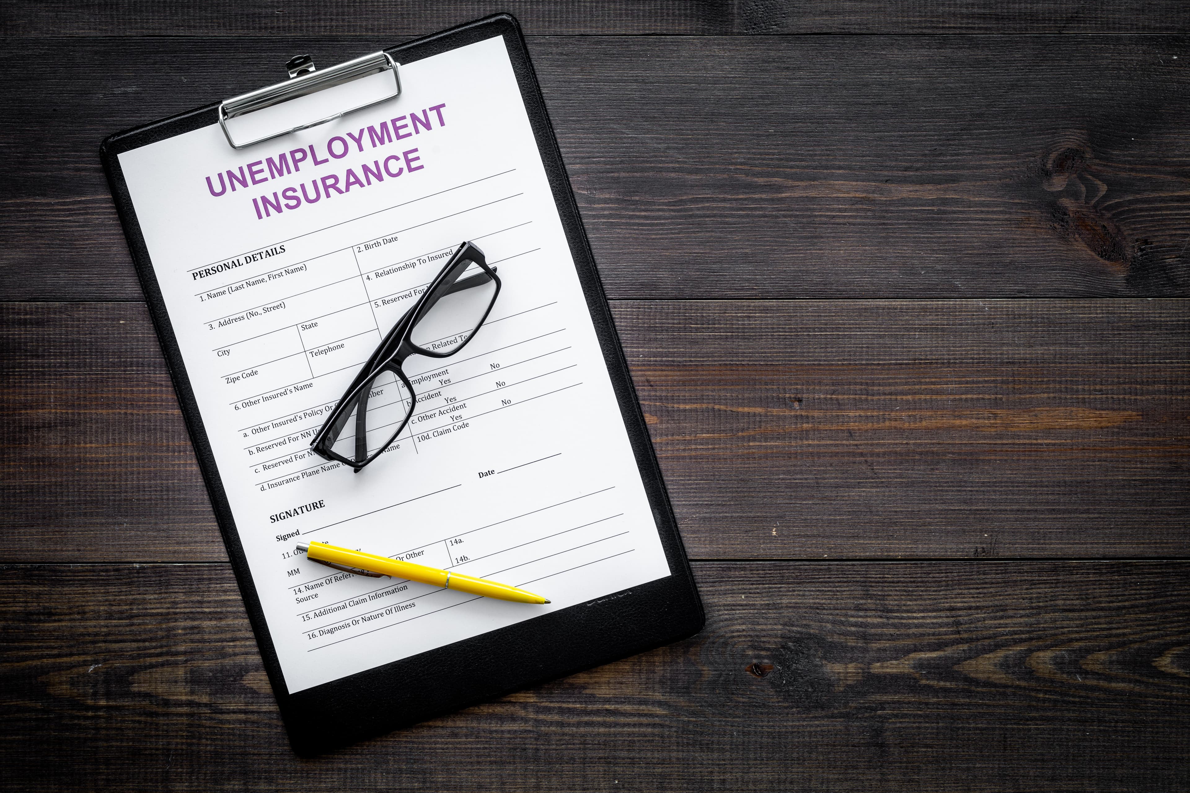 Unemployment insurance form on dark wooden background top view.