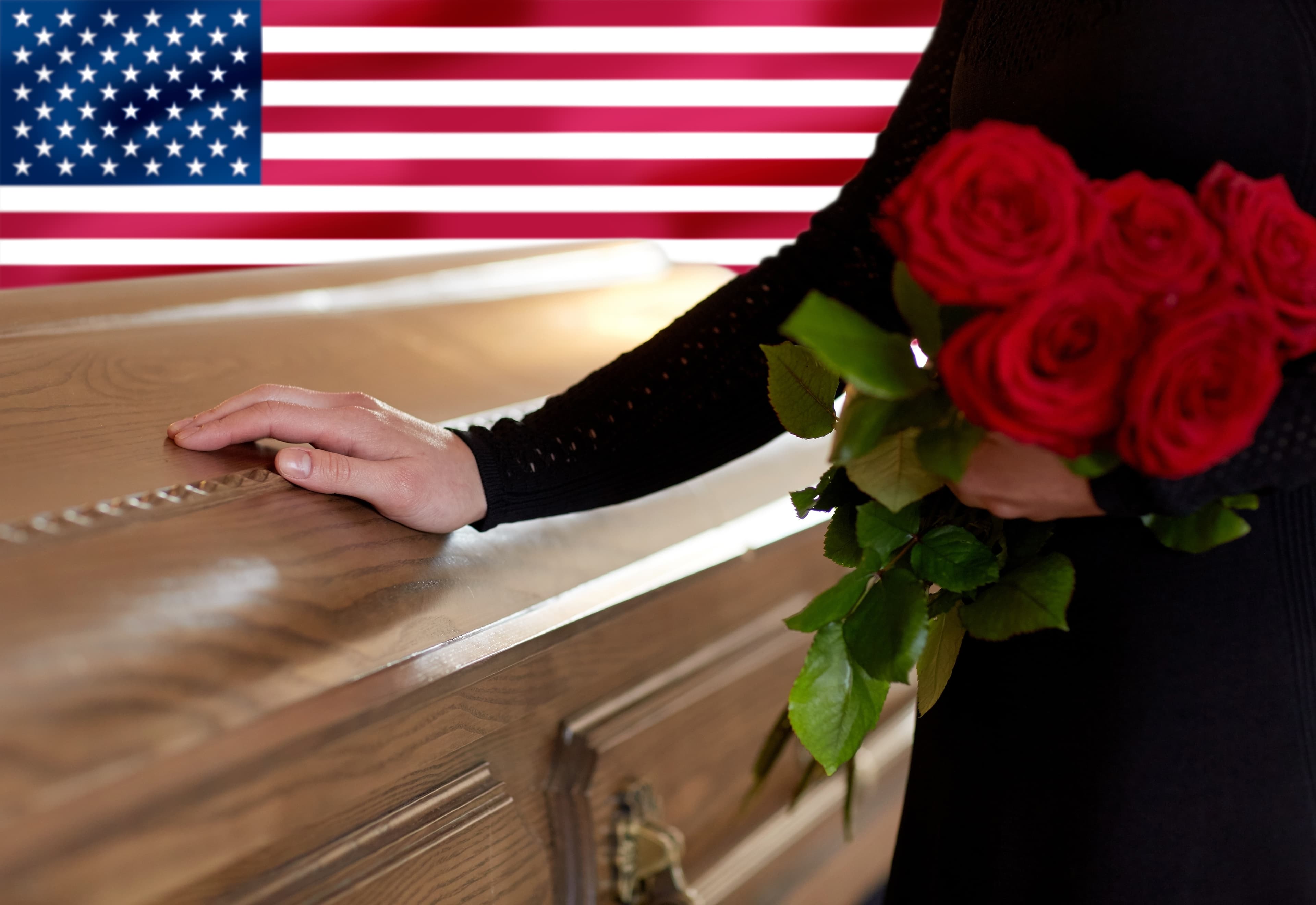 people and mourning concept - woman with red roses and coffin at funeral over flag of america on background