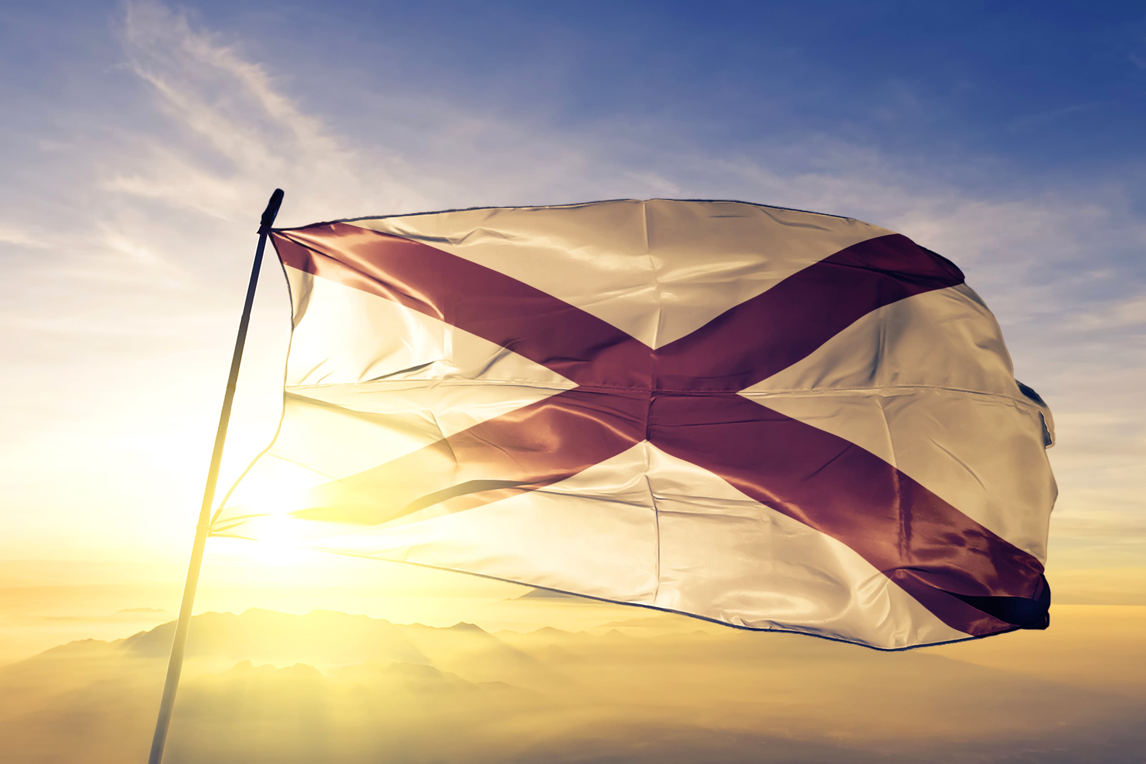 Alabama state of United States flag waving on the top sunrise mist fog