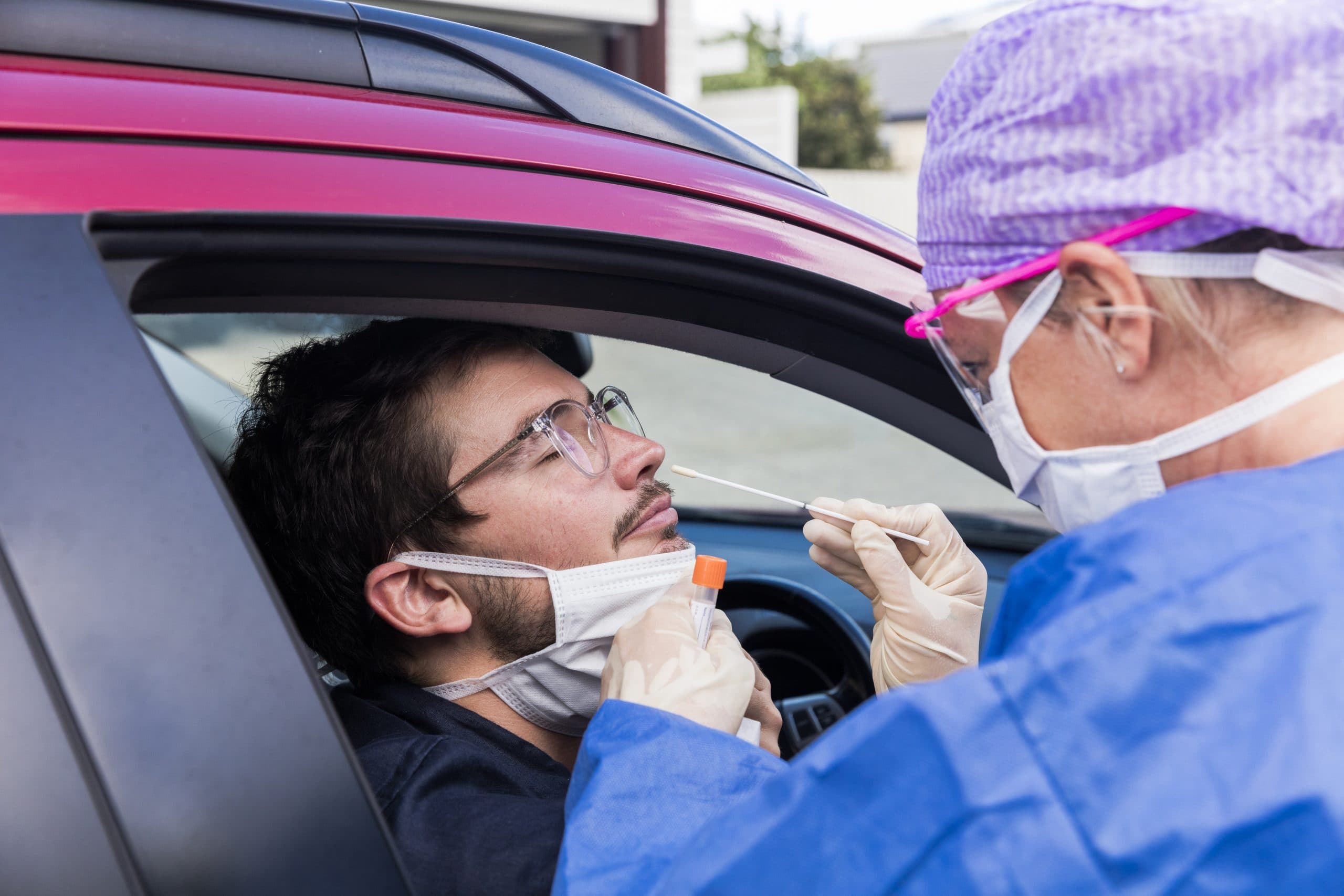 A doctor in a protective suit taking a nasal swab from a person to test for possible coronavirus infection