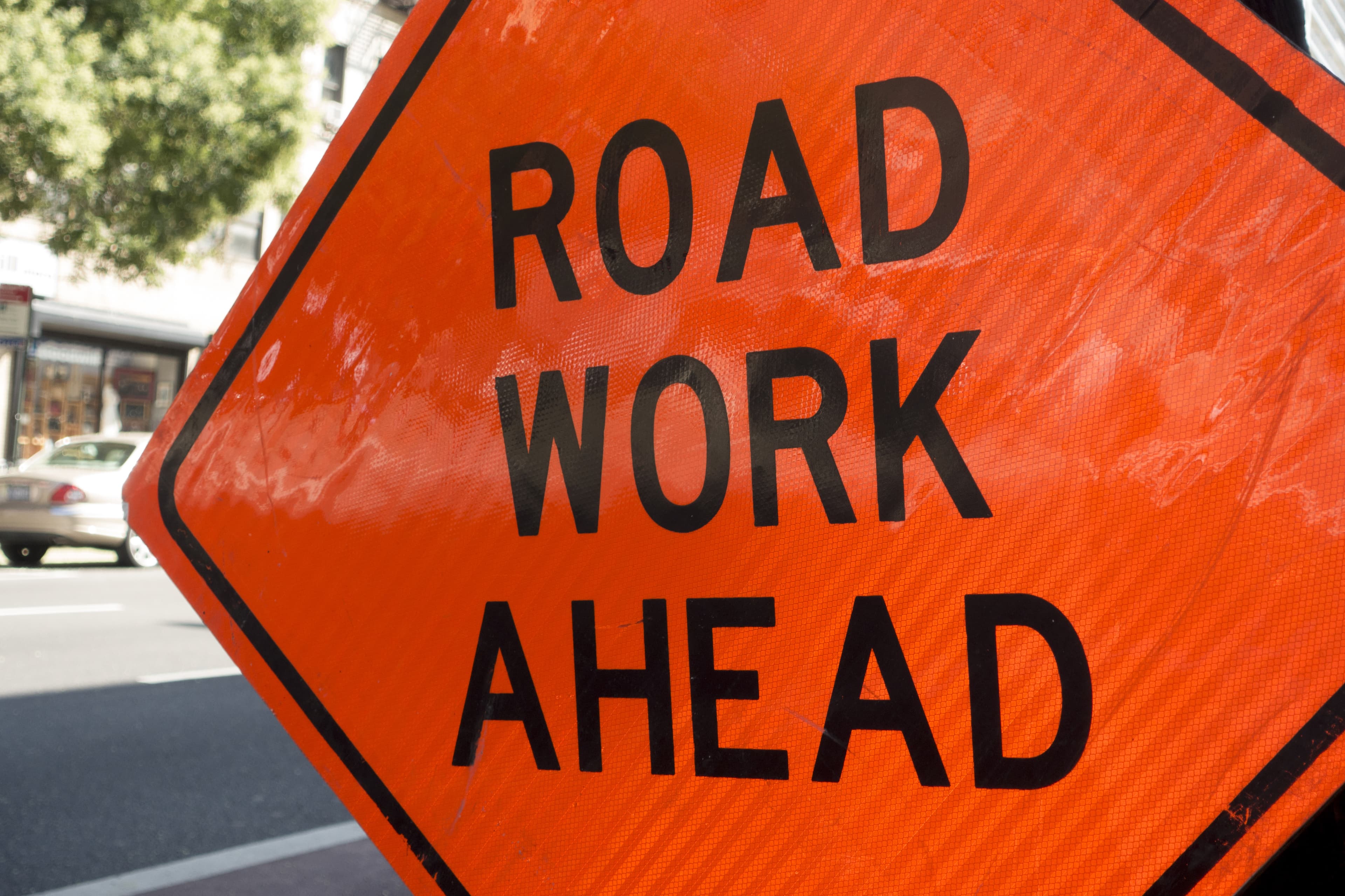 diamond shaped orange red reflector street sign that reads road