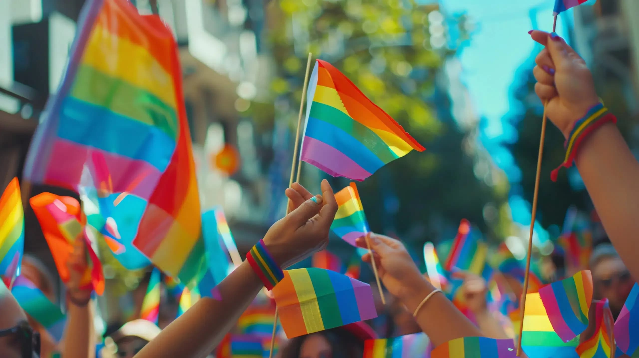 Close-up of hands holding LGBTQ+ pride flags at a colorful parade, capturing the spirit of celebration and solidarity