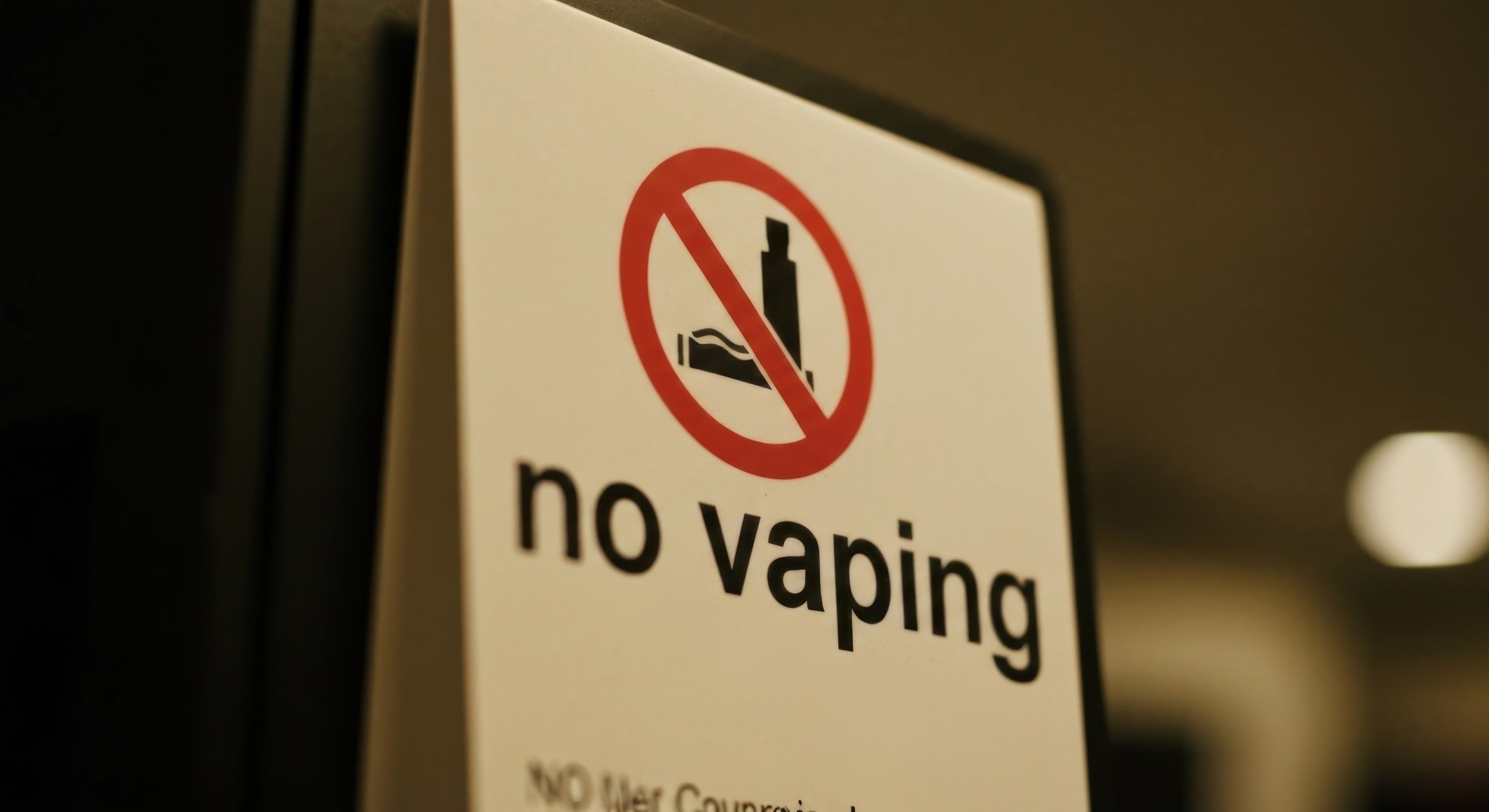 Close-up of a "no vaping" sign, red circle with vape pen and crossed line