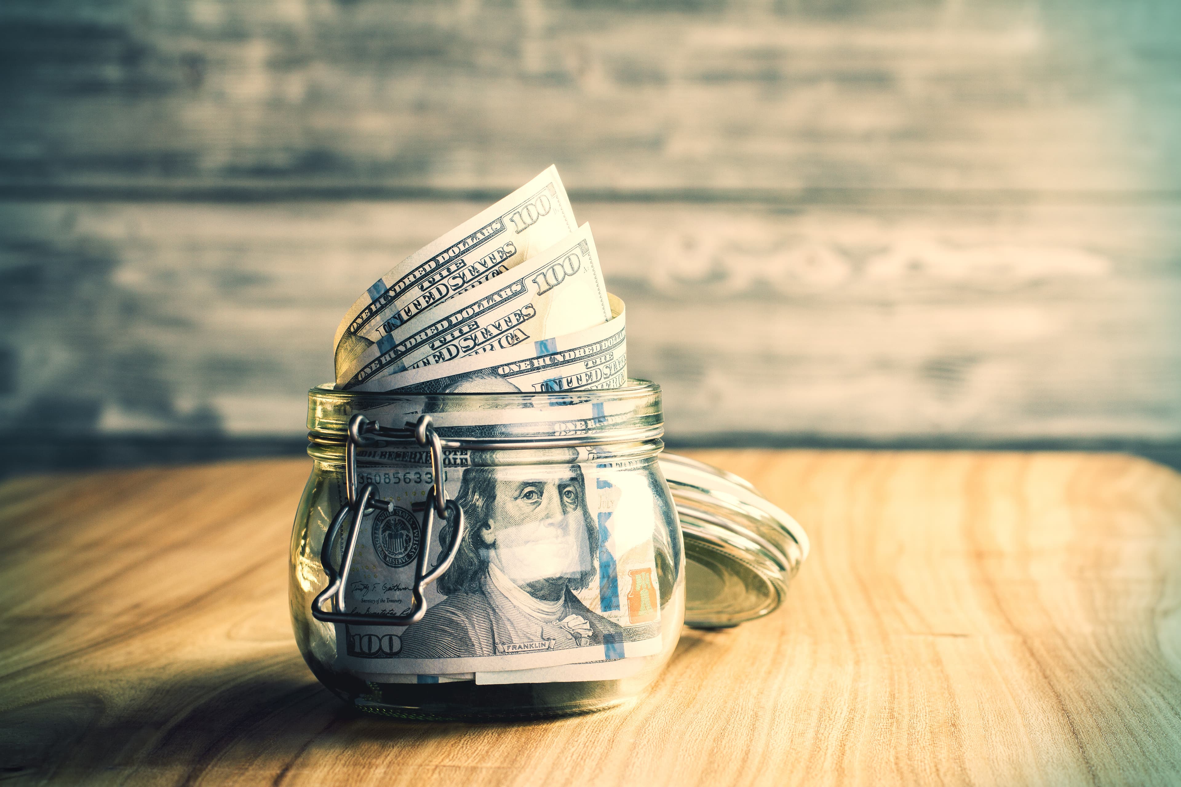 Jar with dollar bills on wooden desktop