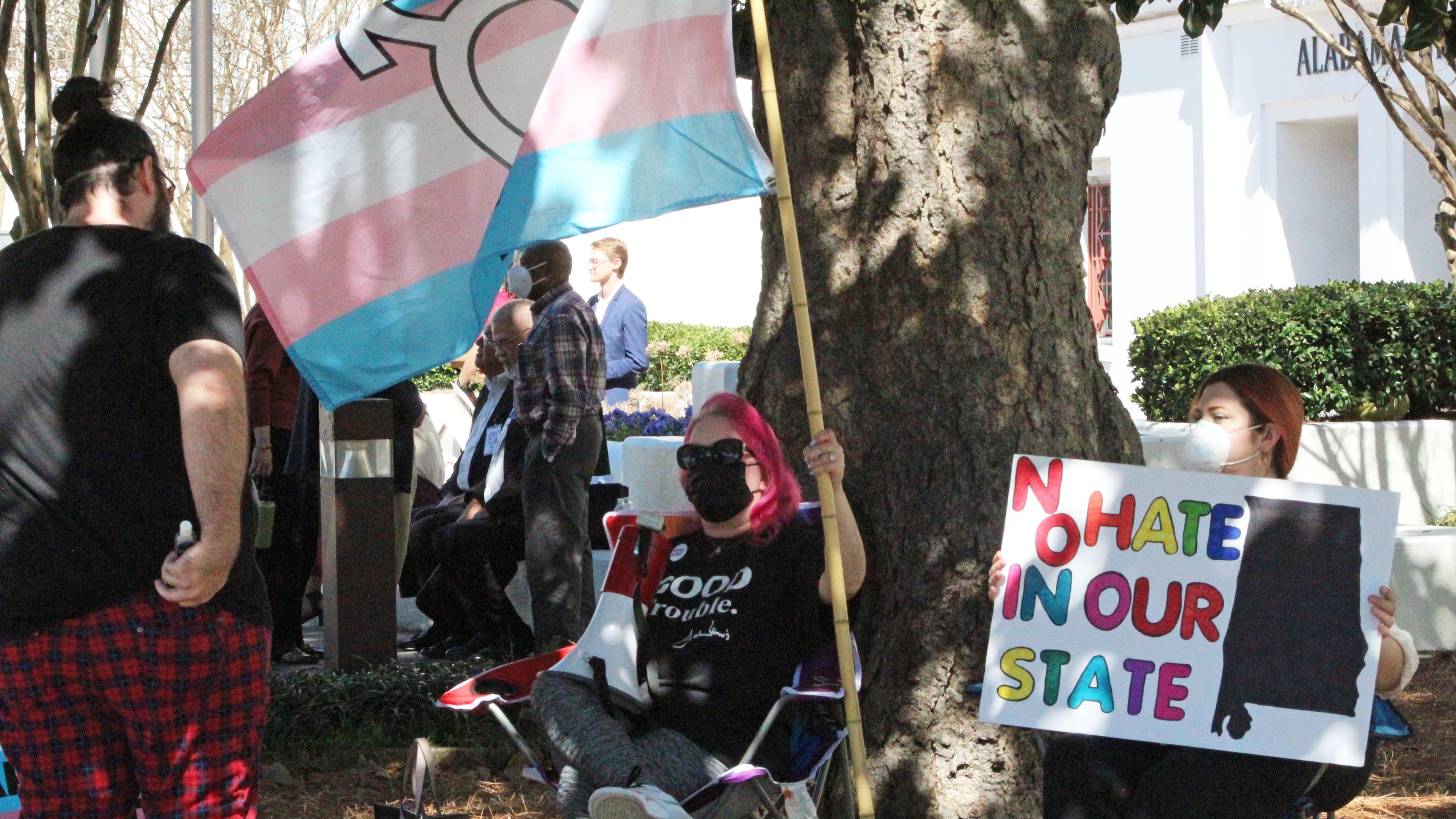 Mia Raven displays the transgender flag alongside a group of protestors outside the Alabama Statehouse on Wednesday opposing a bill that would ban puberty blockers from being prescribed to minors. The bill passed the House Judiciary Committee Wednesday afternoon. (Jacob Holmes / APR)