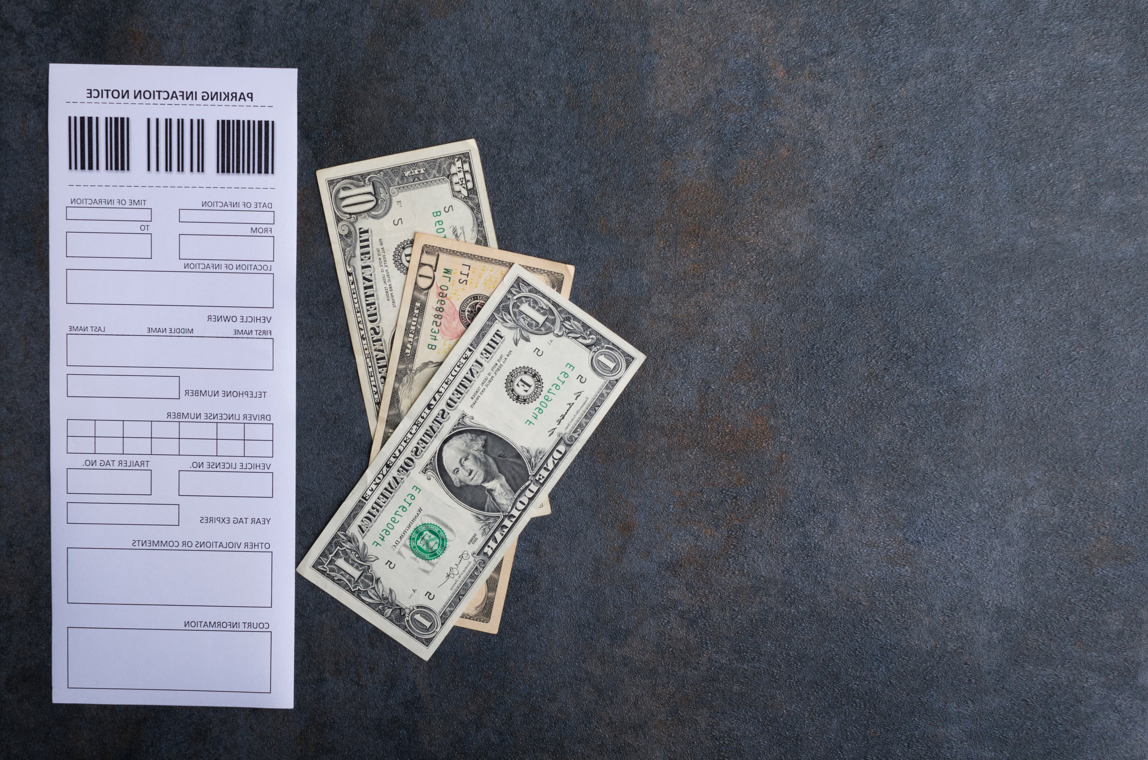 Top view of blank parking violation notice and money for paying