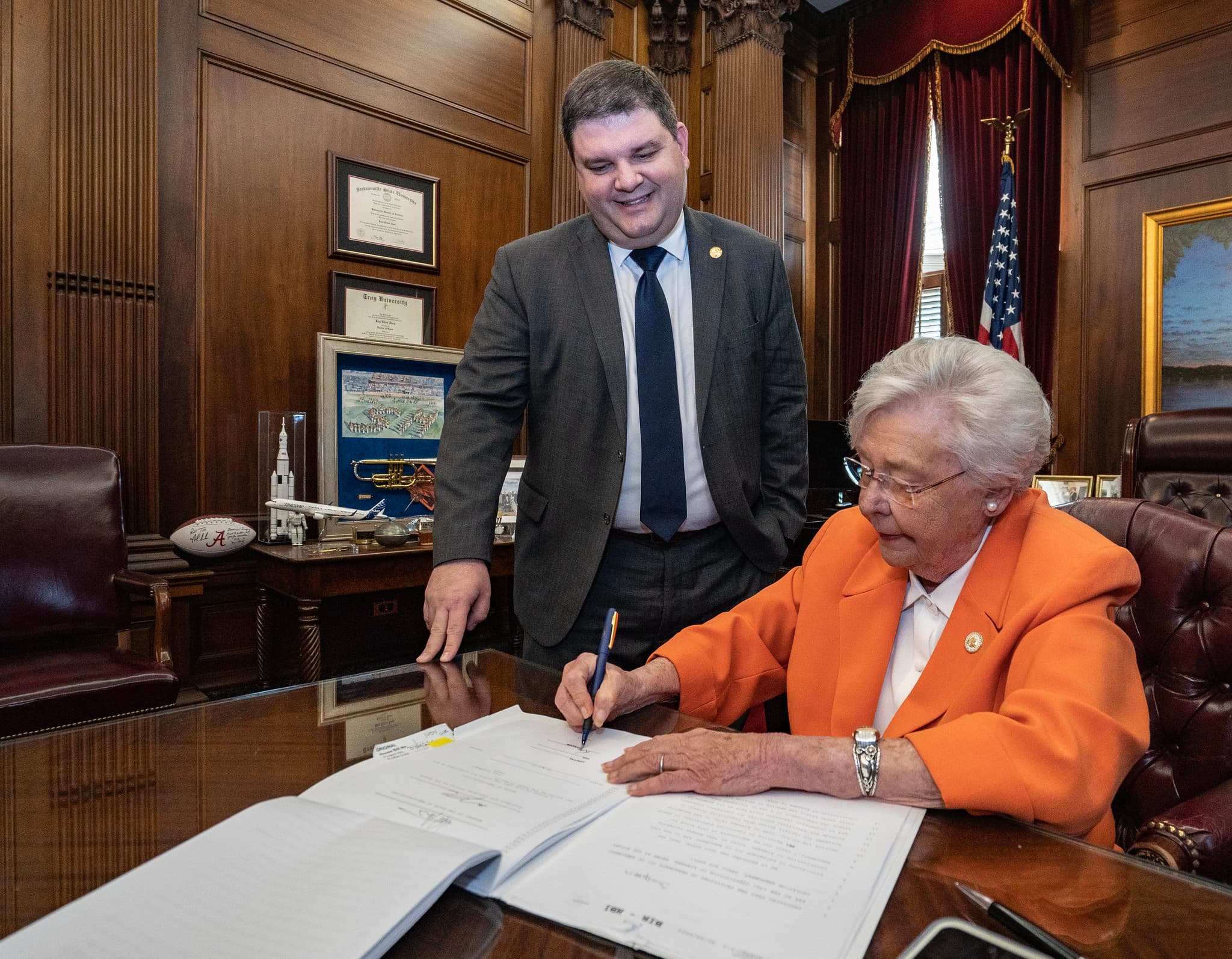 Gov. Kay Ivey signs HB1 setting mandatory minimum sentences for trafficking in fentanyl while the bill's sponsor, Rep. Matt Simpson, R-Daphne, looks on.