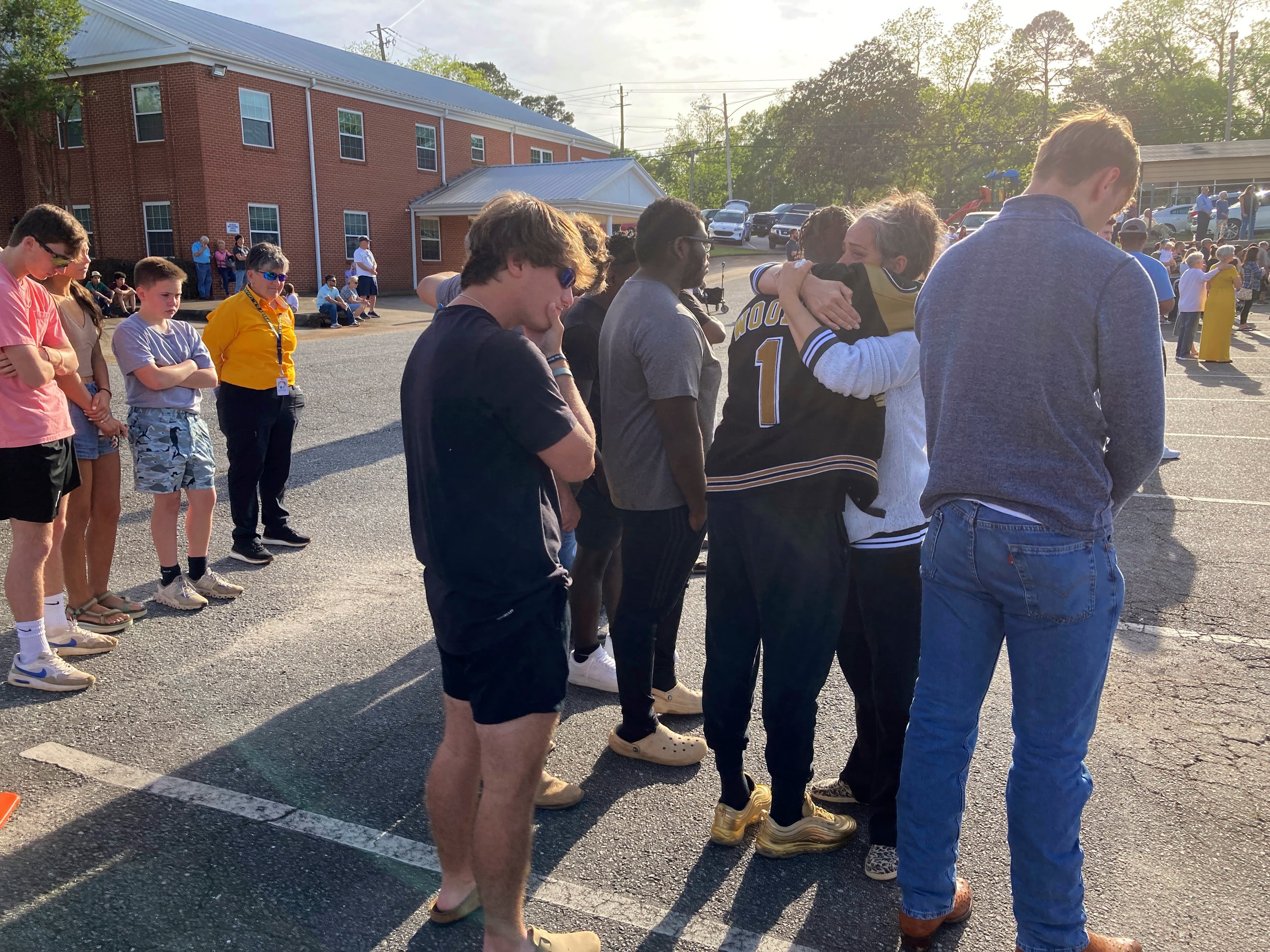 A woman embraces Dadeville High School football player Antojuan Woody at a prayer vigil on Sunday, April 16, 2023, outside First Baptist Church in Dadeville, Ala. Alabama law enforcement officers were imploring people to come forward with information about a shooting that killed multiple people and injured over two dozen others during a teenager's birthday party on Saturday, April 15.