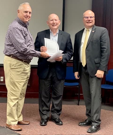 Alabama-Tombigbee Regional Commission Executive Director John Clyde Riggs (left) presents a resolution expresing the commission’s support for the West Alabama Highway to ALDOT Director John Cooper (center). Thomasville Mayor Sheldon Day (right) participated in the presentation, which was held during the commission’s meeting in Thomasville.