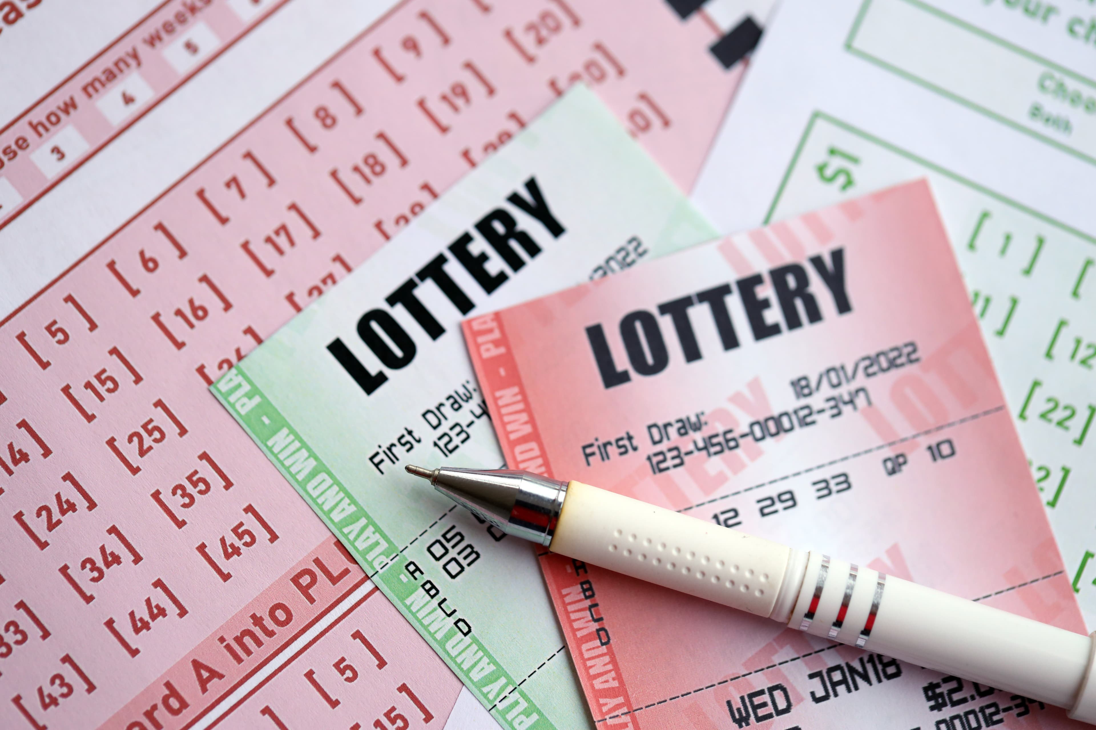 Green and red lottery tickets with pen on blank bills with numbers for playing lottery