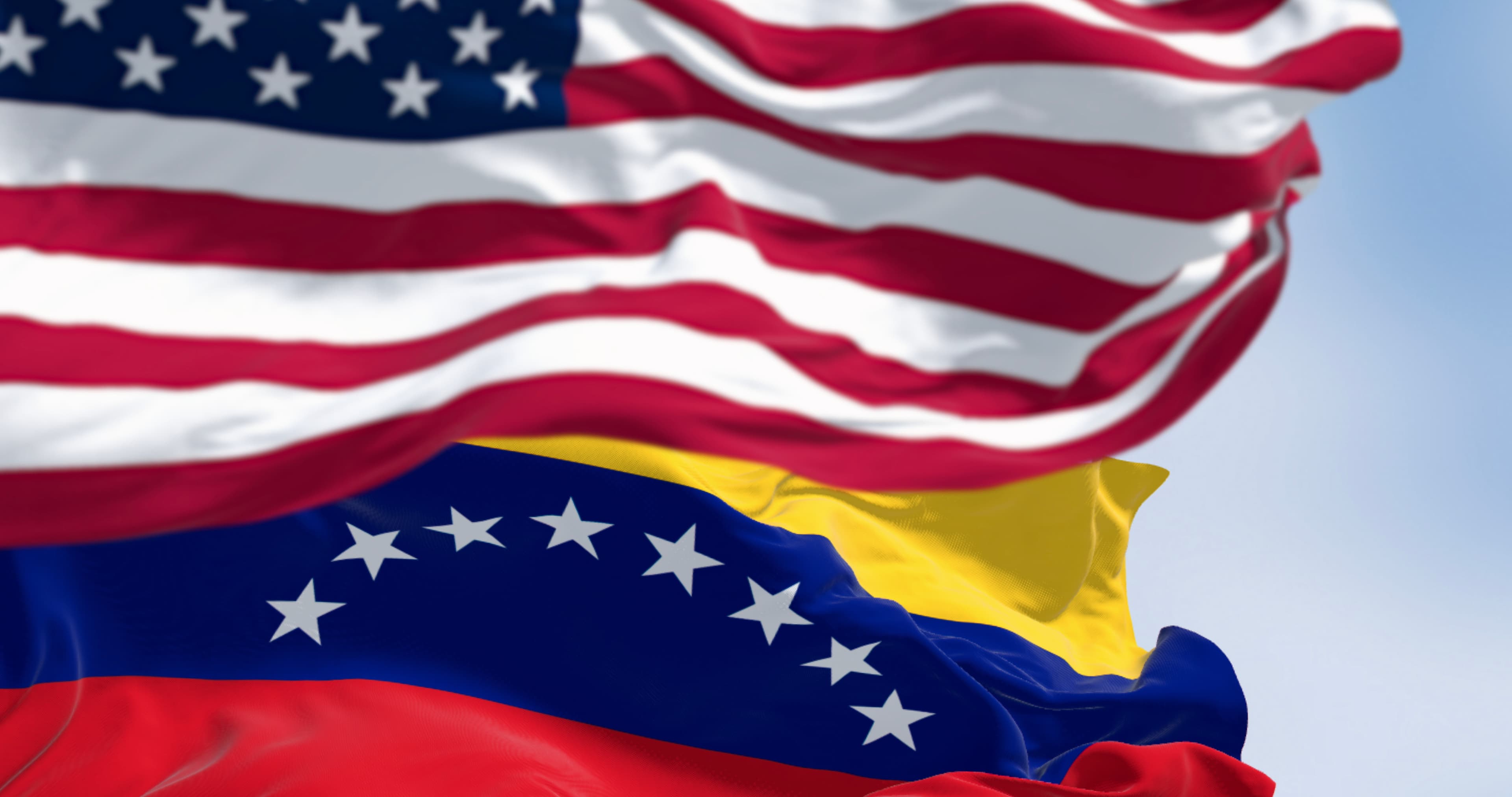 Venezuela and US national flags waving in the wind on a clear day