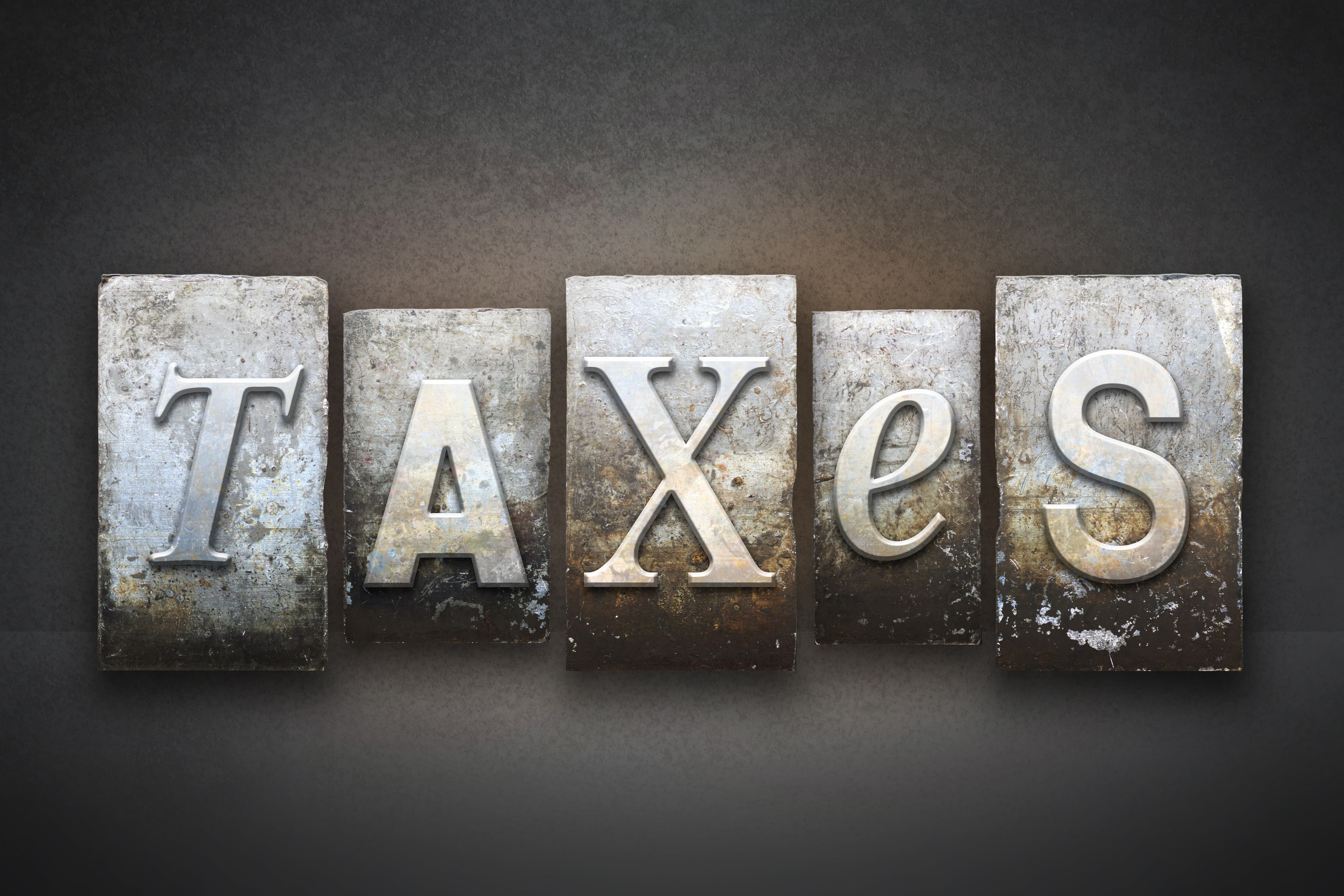 The word TAXES written in vintage letterpress type