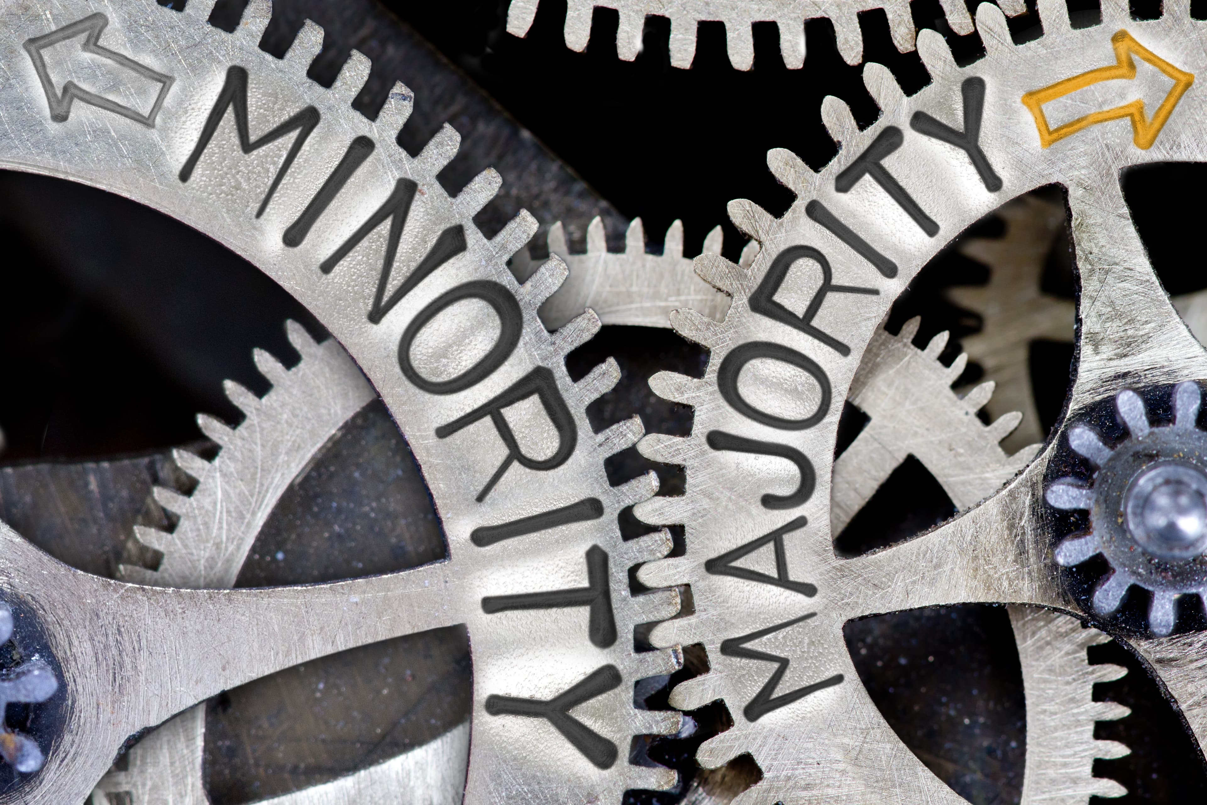 Macro photo of tooth wheel mechanism with imprinted arrows and MINORITY, MAJORITY concept words