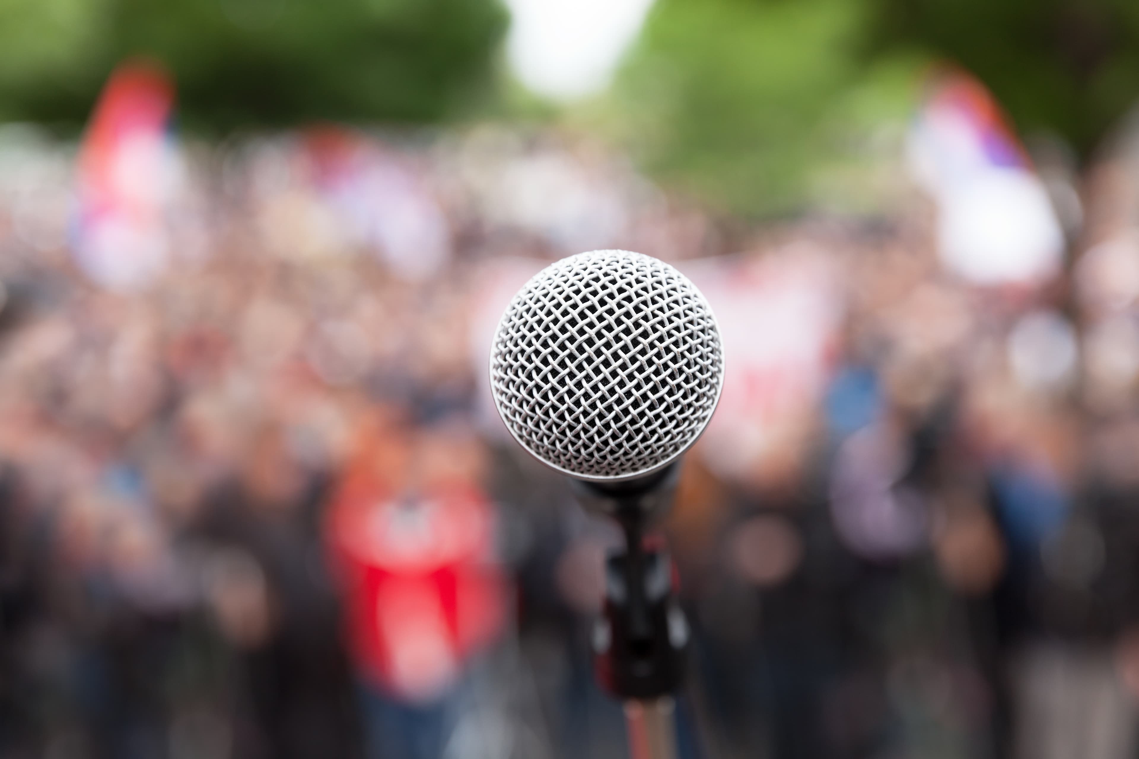 Microphone in focus against blurred audience. Political rally.