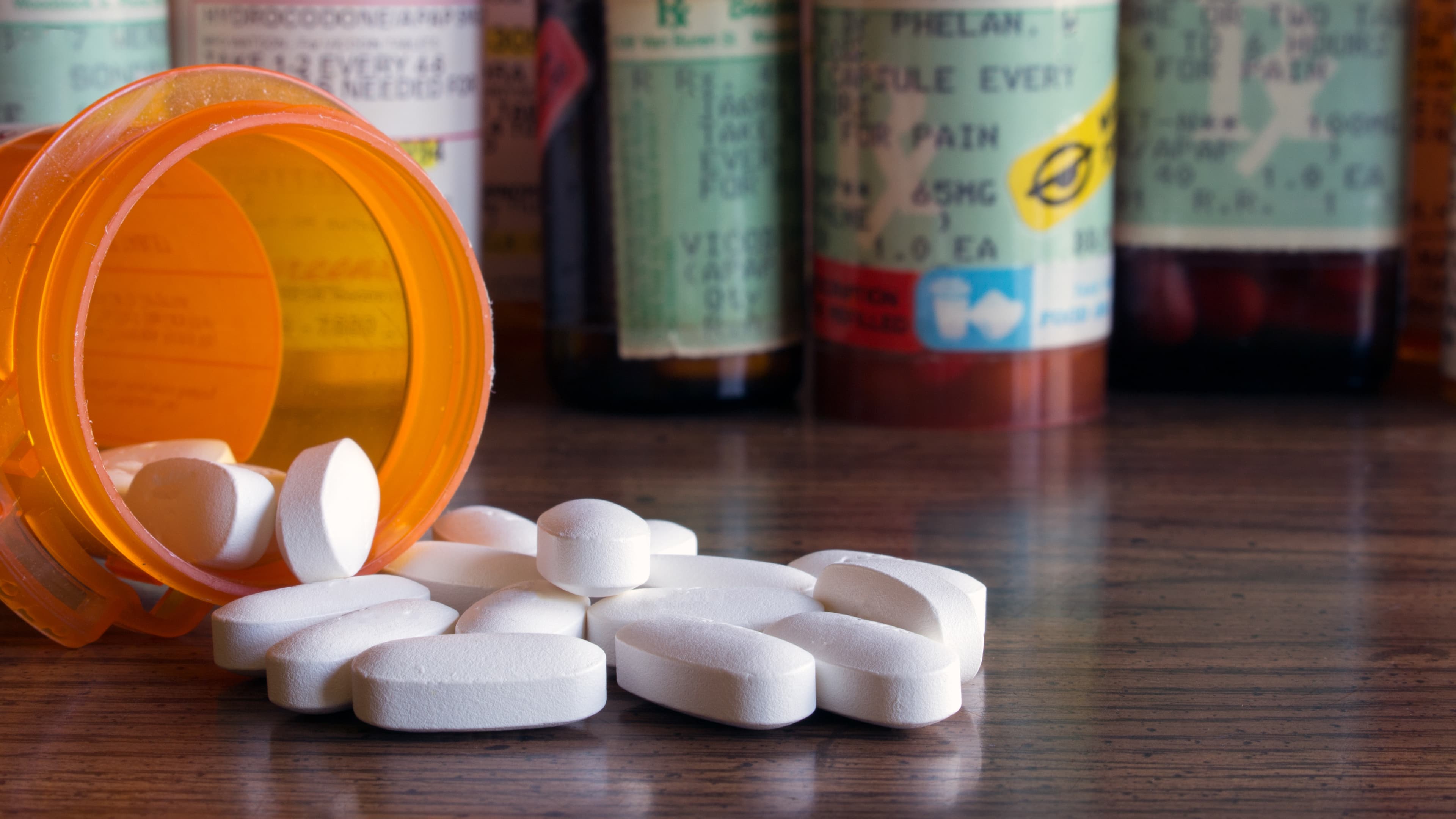 Prescription opioids with many bottles of pills in the background. Concepts of addiction, opioid crisis, overdose and doctor shopping