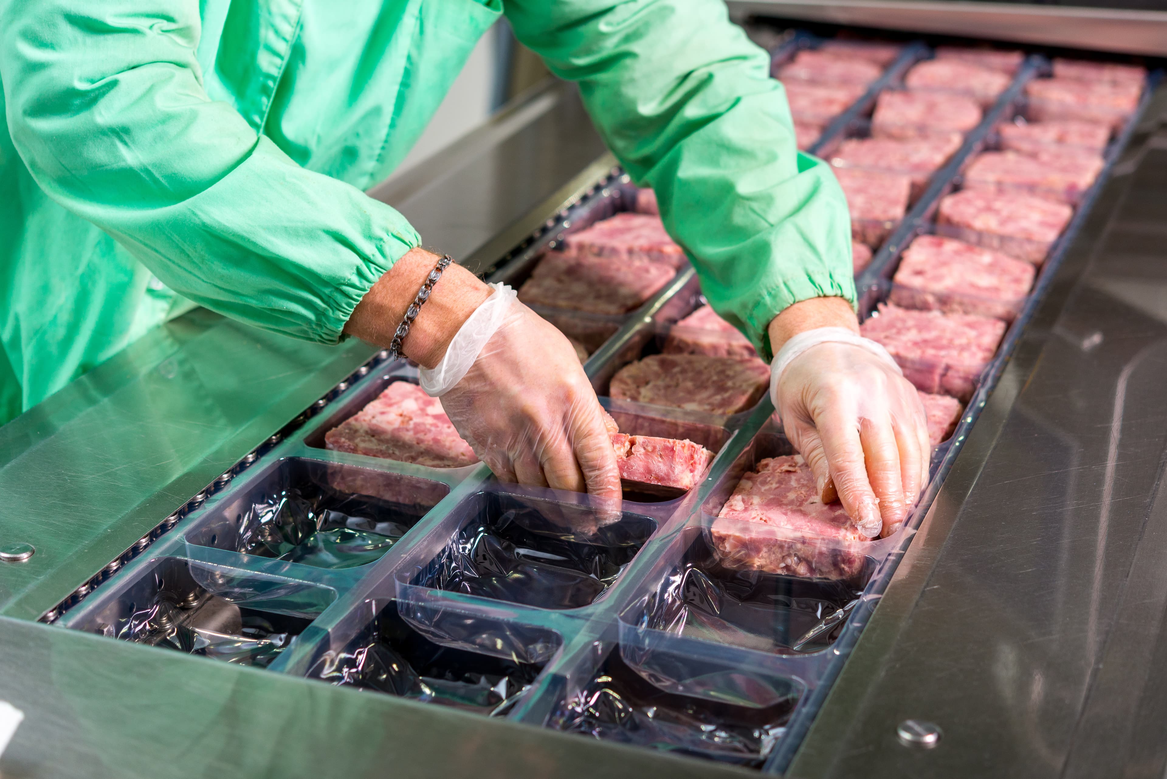 Several chunks of raw meat being processed packaged and shipped